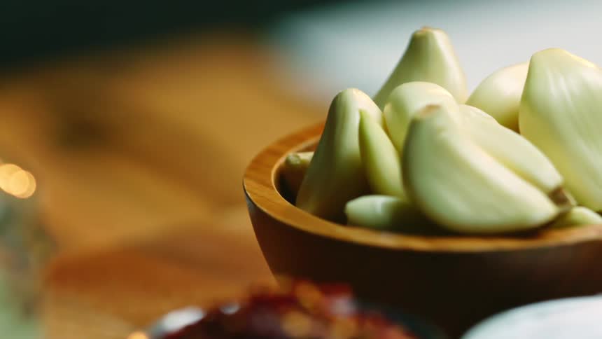 The bowl on the table is full of garlic cloves