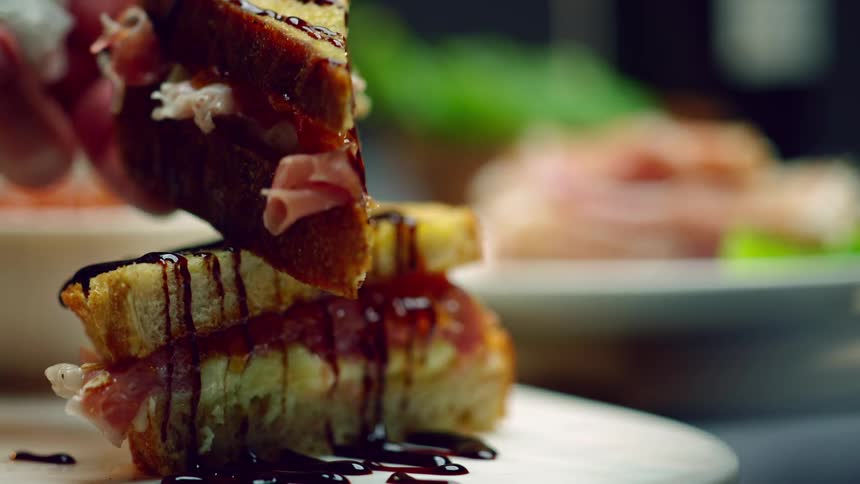 A person drizzling chocolate onto a pastry on a plate on a table