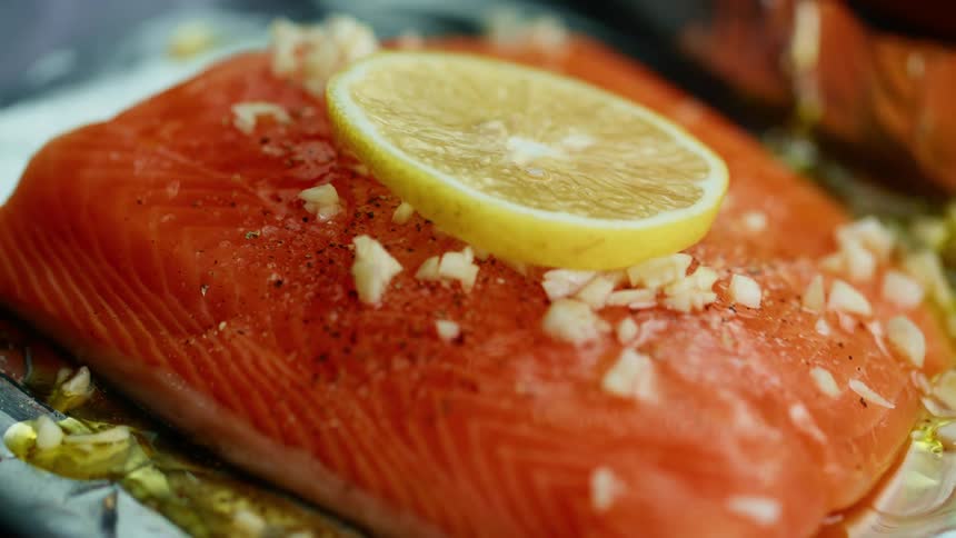Salmon on a plate with a lemon being placed on top
