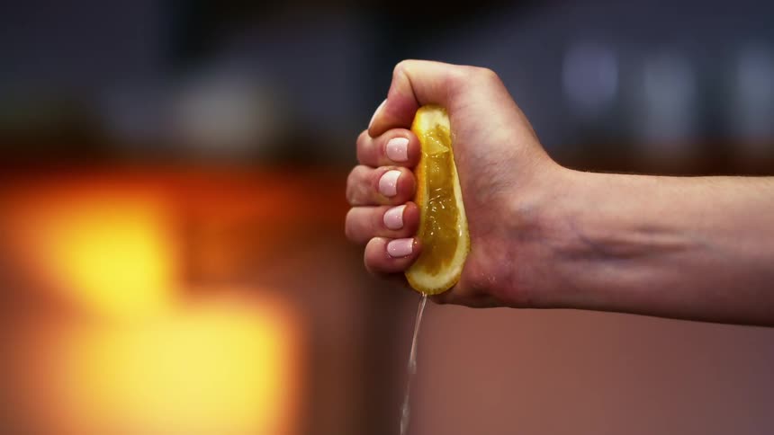 Womans hand squeezes half lemon