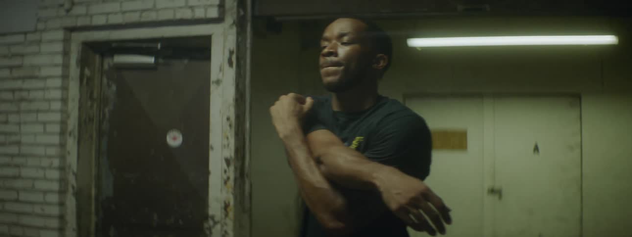 Black male stretches his arms by placing them over each other in front of his chest