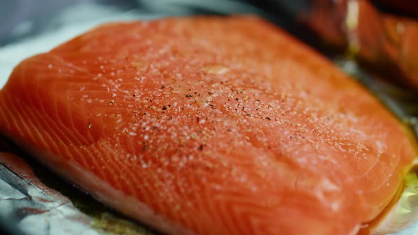 Seasoning is sprinkled on the fish