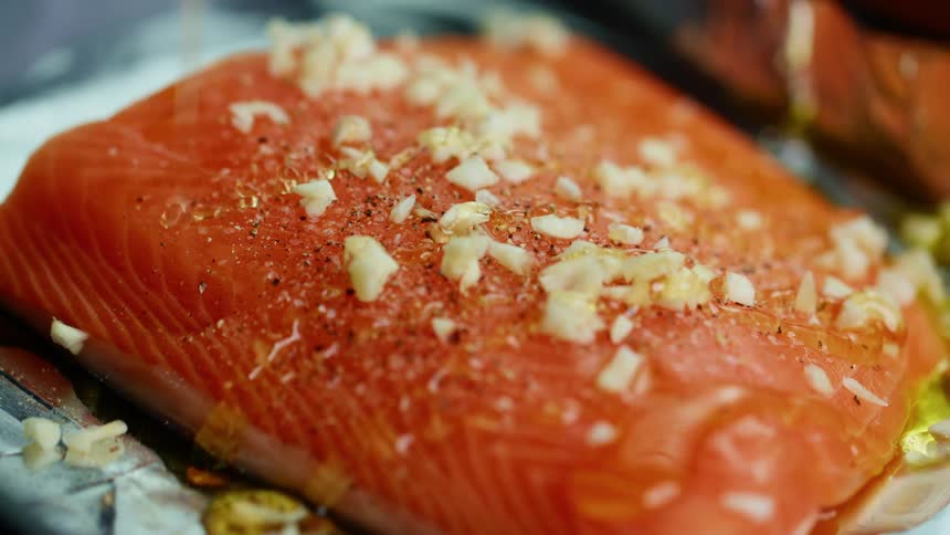 Oil is poured over a piece of salmon
