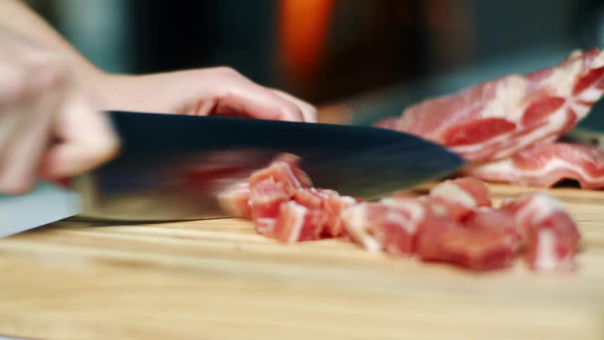 A person is dicing up some meat