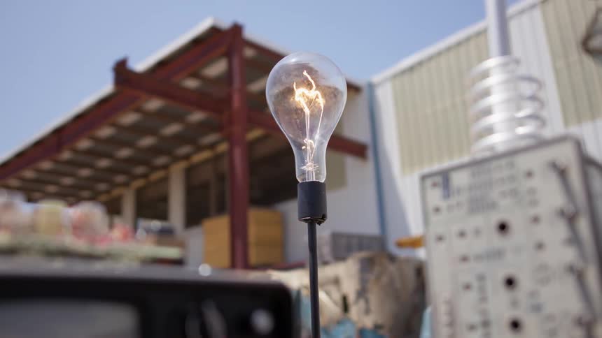 A light bulb turns on as part of an electrical set up outside a building