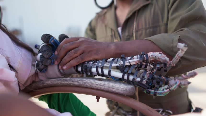 A man attaches a futuristic robotic arm on to a woman