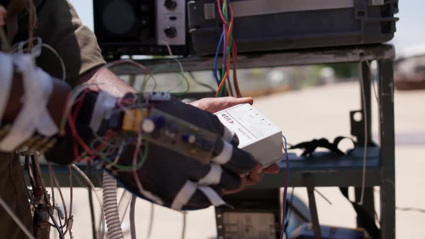 A man is wearing a glove covered in wires