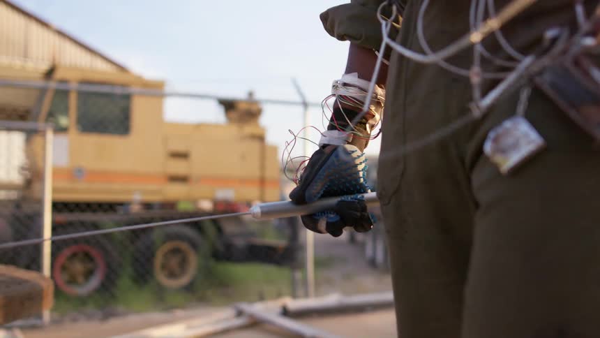 A man covered in wires walks through the lot