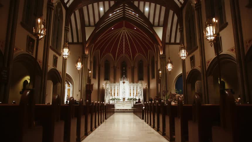 Interior of a church with the altar in the background with some people walking outside the pews