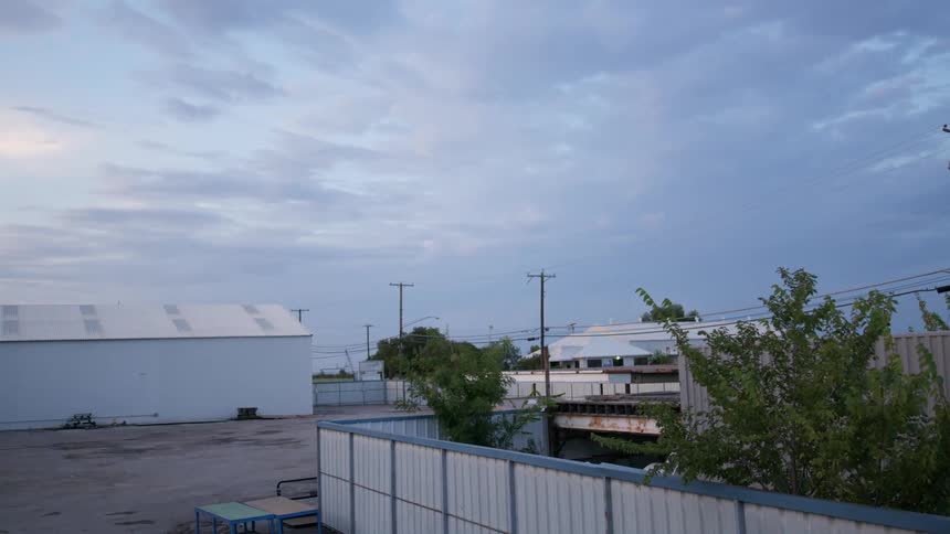 Parking lot separates warehouses under cloudy sky