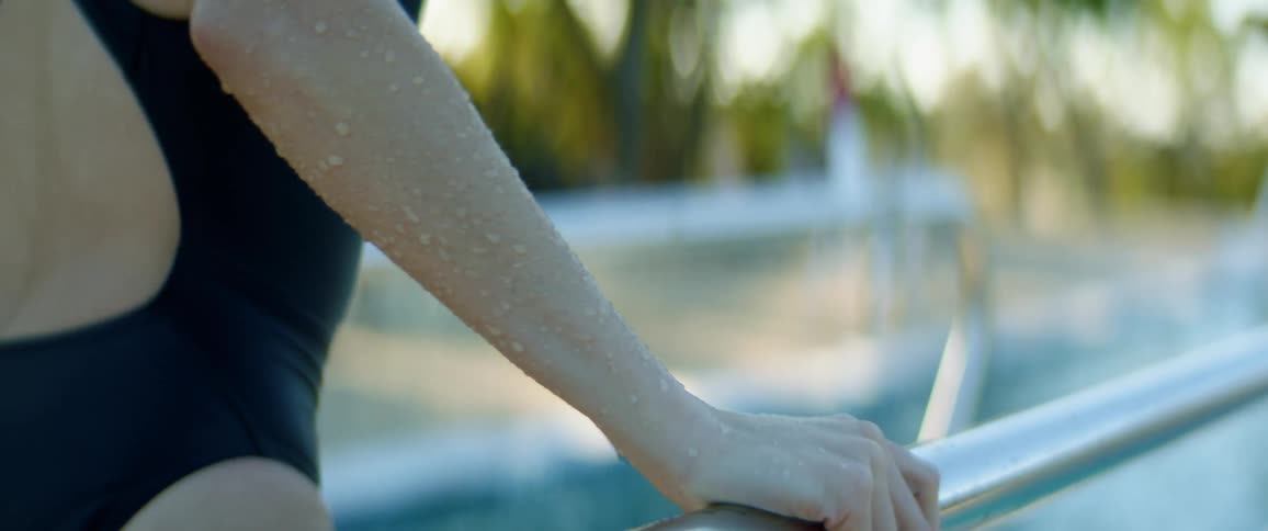A female walking on a pool diving board outside