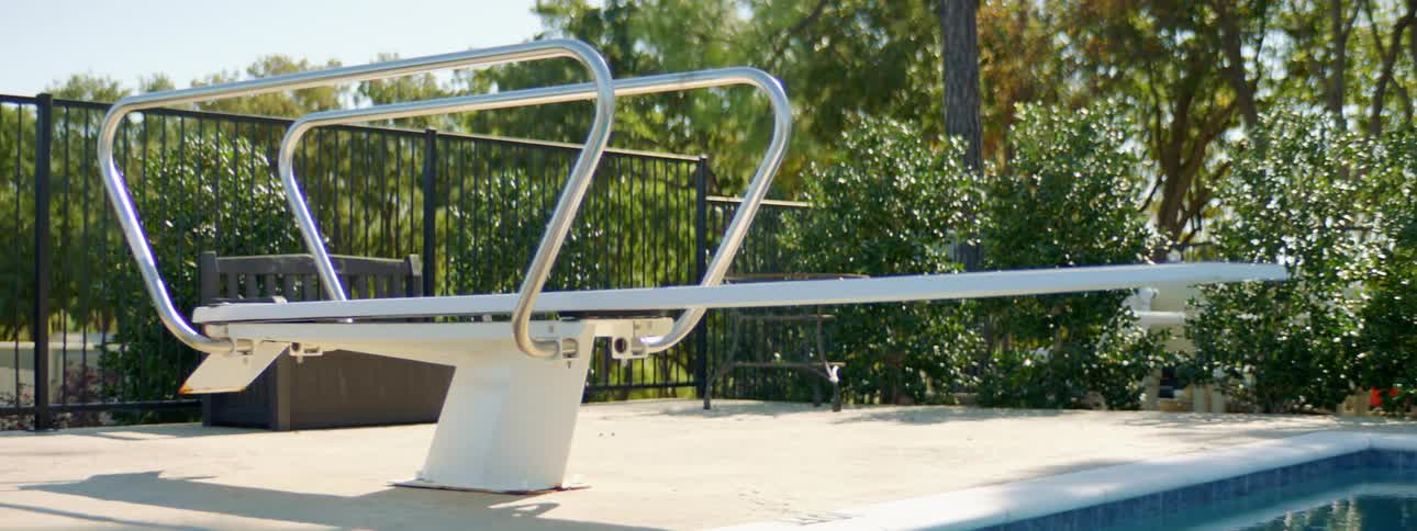 A diving board that is on the edge of a swimming pool at a park