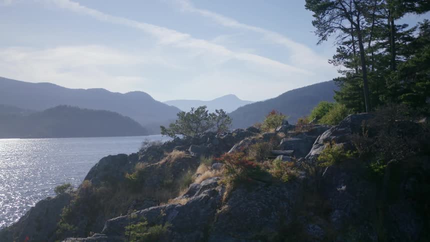 Water meeting a rocky shore with mountains in the distance