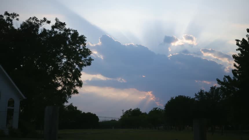 The sun hides behind dense clouds over a neighborhood