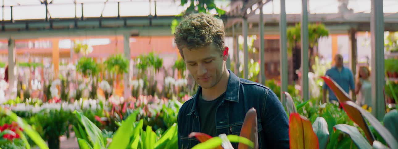 A man is shopping for plants in the garden center of a big box store during the day