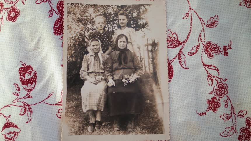 A vintage photograph of four women sits on a tablecloth