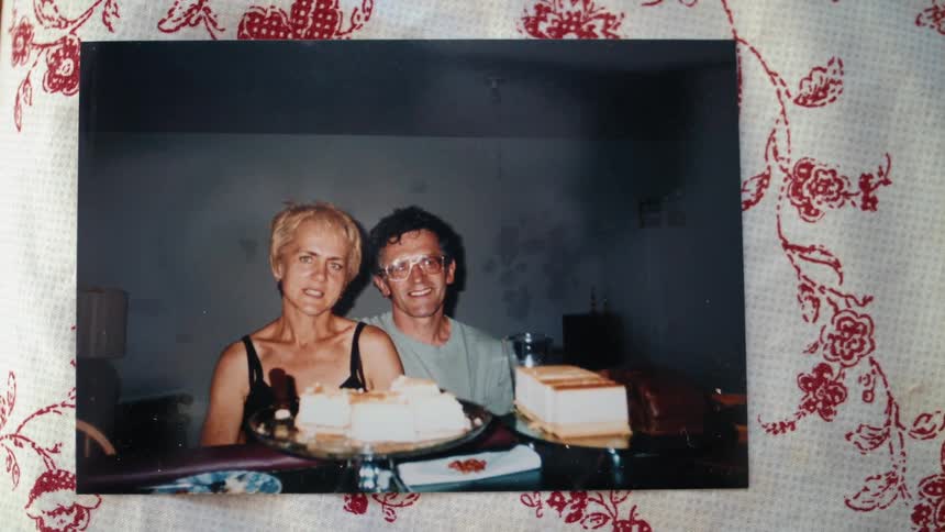 A shot of a framed photograph of a man and woman sitting at a table looking at the camera