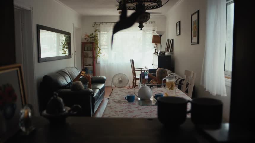 Elderly woman and elderly man lie on the opposite sofas and use smartphones in the living room
