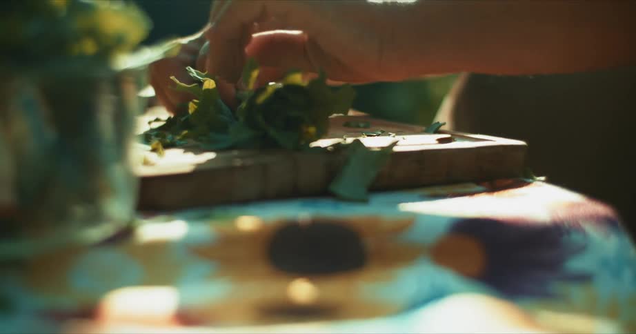 A man rolls up herbs to chop them