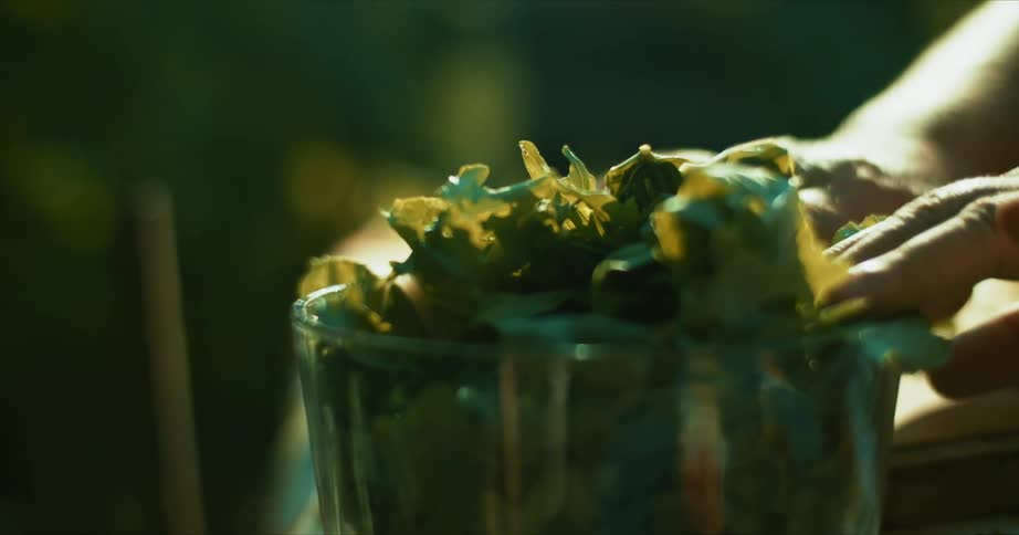 A man packs pieces of cut lettuce into a clear bowl while outside