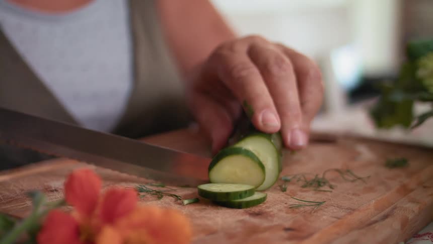 Woman cuts a cucumber on a cutting board
