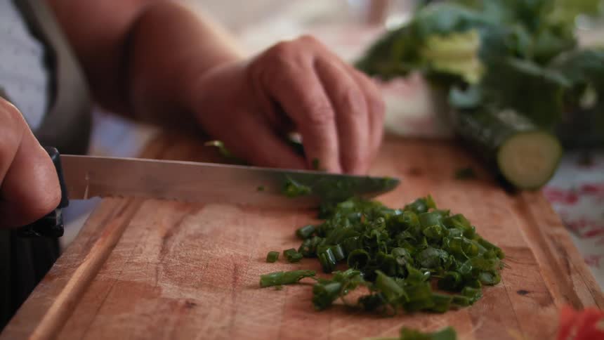 A person cutting spring onions on a chopping board