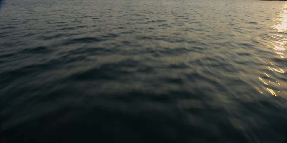 Moving fast over a body of water towards a city at sunset