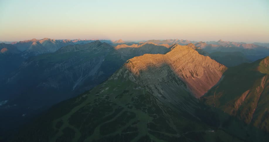 A mountain slope covered in vegetation leading up to a barren summit