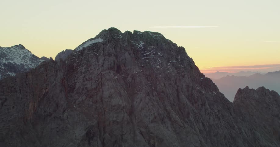 A stone mountain ridge peppered with snow in the evening