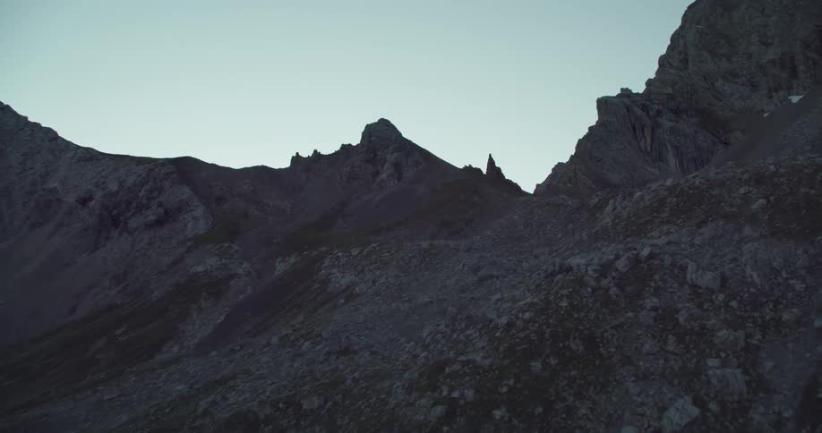 A trail runs along the flat portion of a mountain below the peak