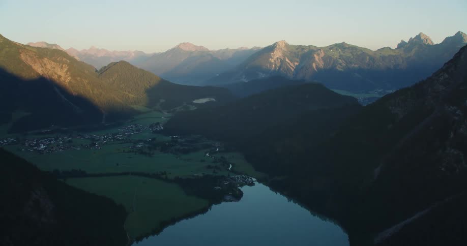 A town next to a lake in the valley of a mountain range during the day