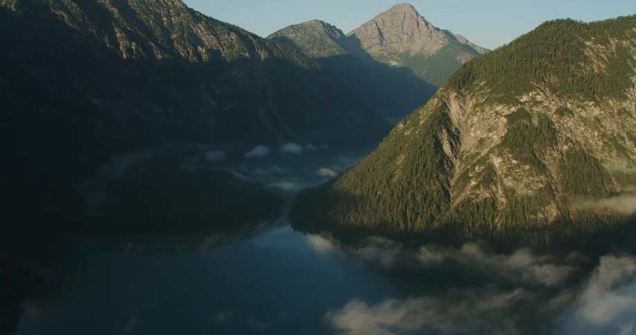 The sky and clouds are reflected onto the surface of a lake in a canyon