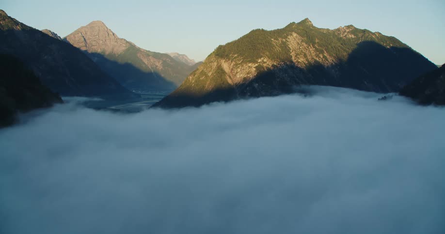 Tree covered mountains peak above heavy fog