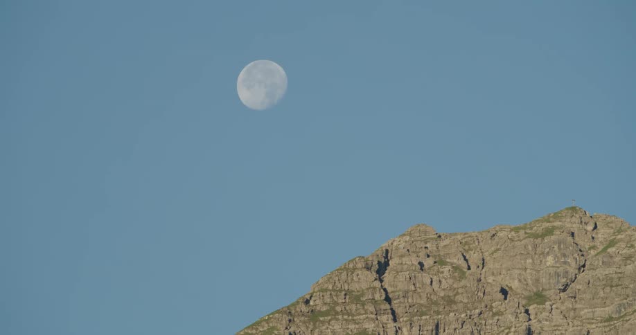 The waning gibbous moon in the evening sky about a mountain ridge