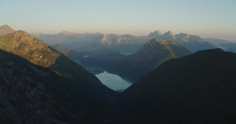 A lake in the foggy valley off a mountain range on a sunny day