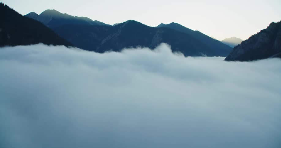 Thick clouds shroud the valley between mountain ridges during the day