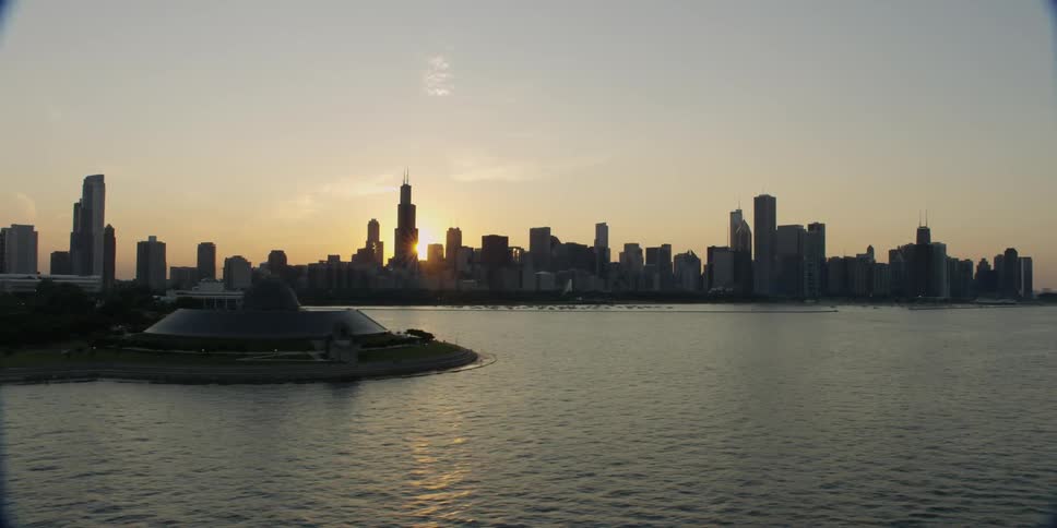 The sun shines through a city skyline
