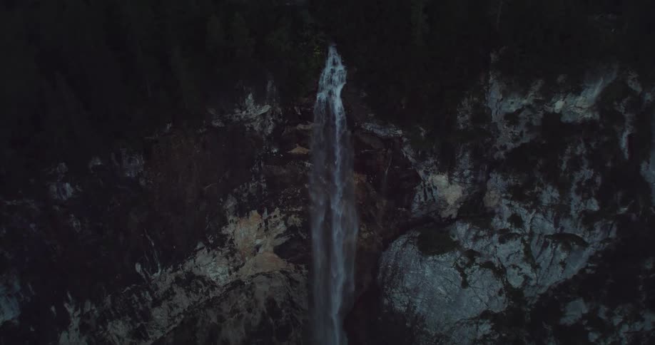 An aerial view of a waterfall flowing over a cliff in the wilderness