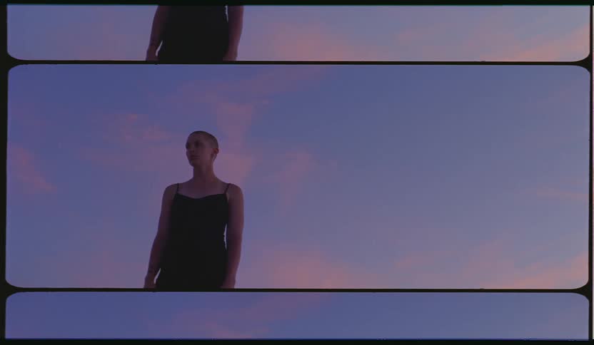 A woman standing outside with the sky and clouds in the background