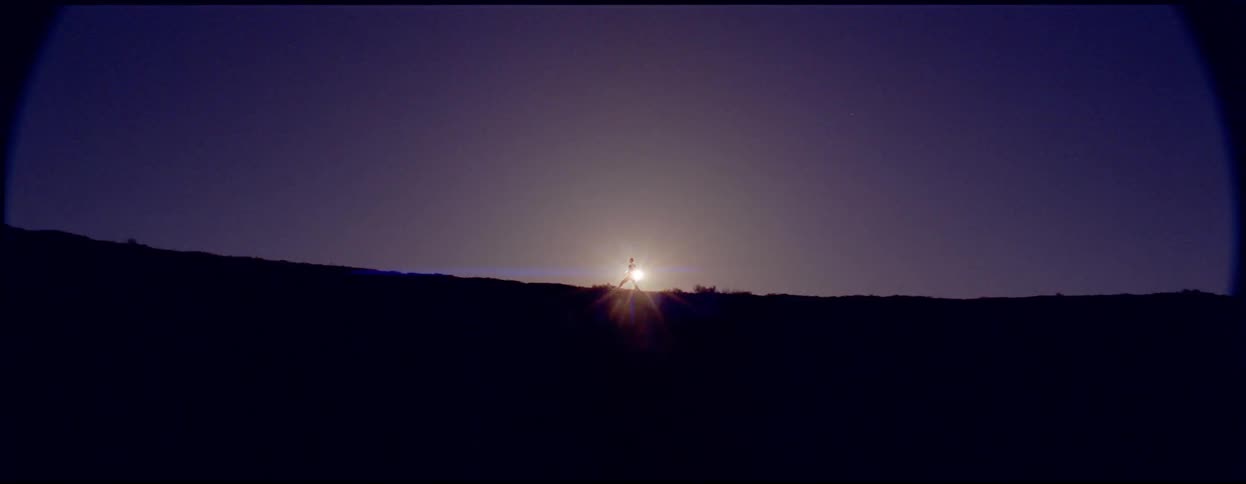 Person leaping and jumping in front of sun on top of ridge