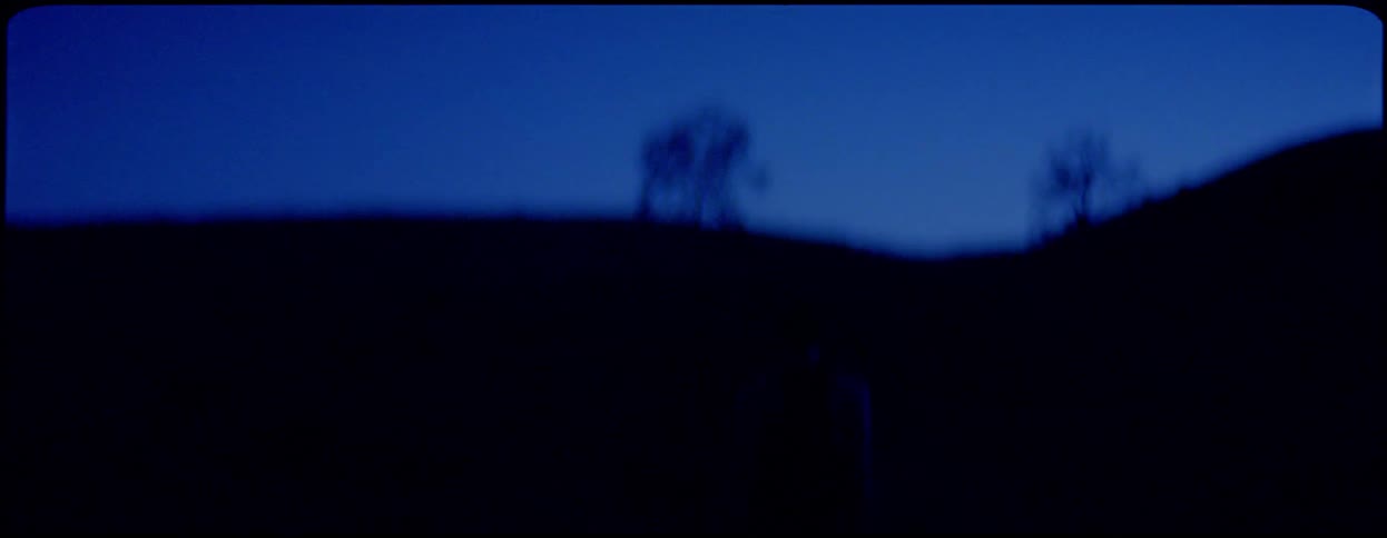A woman walks up a hill as the night shrouds her figure