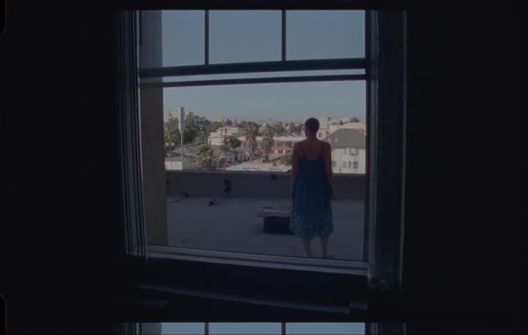 A woman crawls out of the window and walks out on to the rooftop balcony
