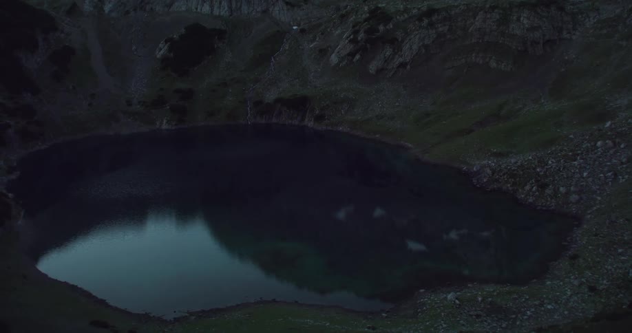 A small reflective lake sits at the base of a canyon