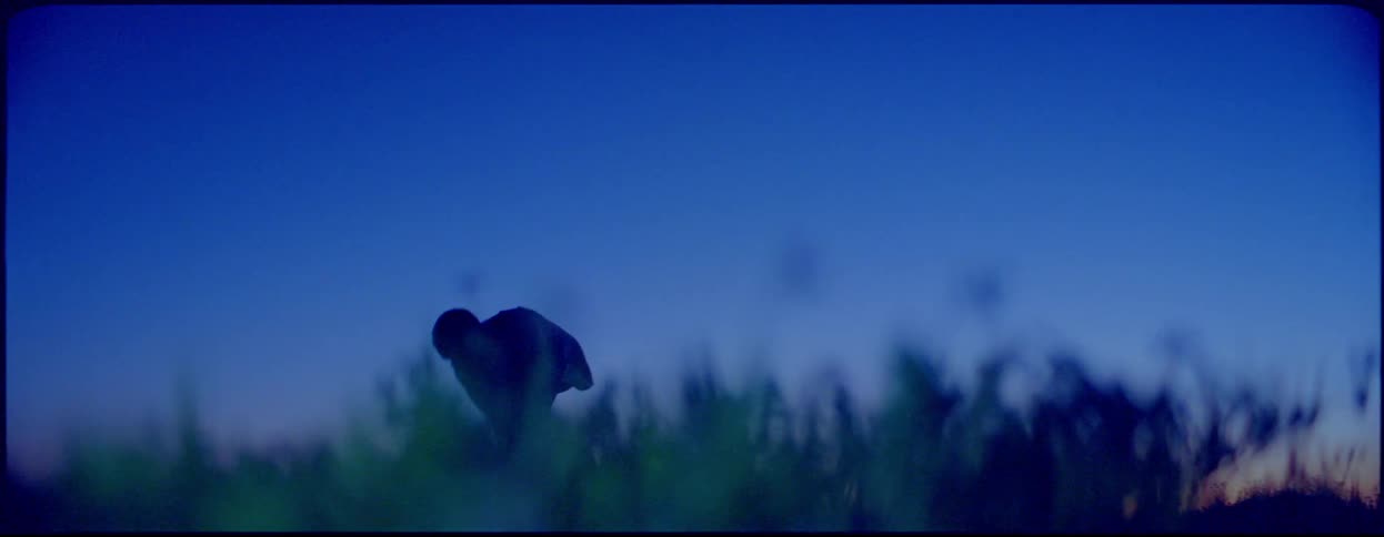 A silhouette of a woman dancing with the sky and clouds in the background