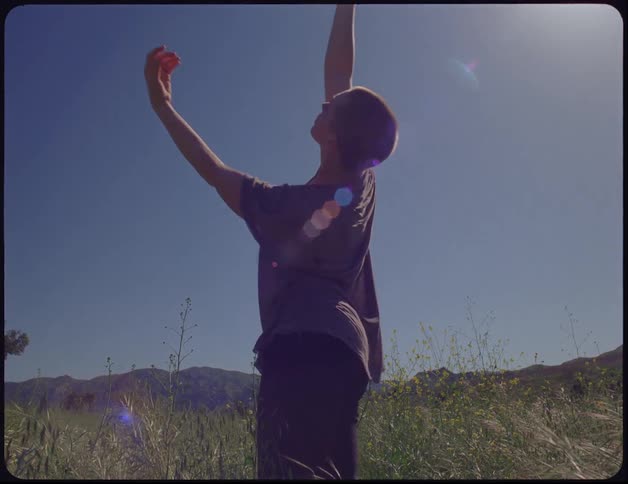 A young woman dances in a field of grass on a sunny day