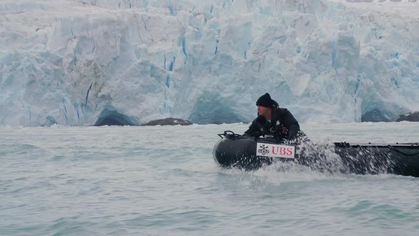Two men ride a raft boat on choppy artic waters