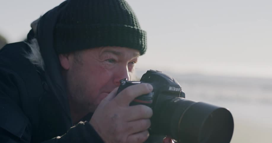 A photographer on the beach with his camera