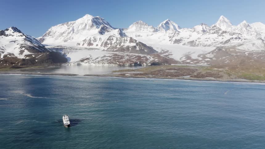 A boat is moving across the ocean near the mountains