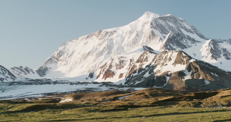 A large rocky mountain stands tall and is covered in a layer of snow