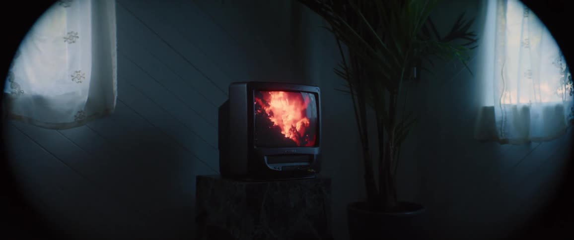 A crt television on a marble television stand displaying a forest fire